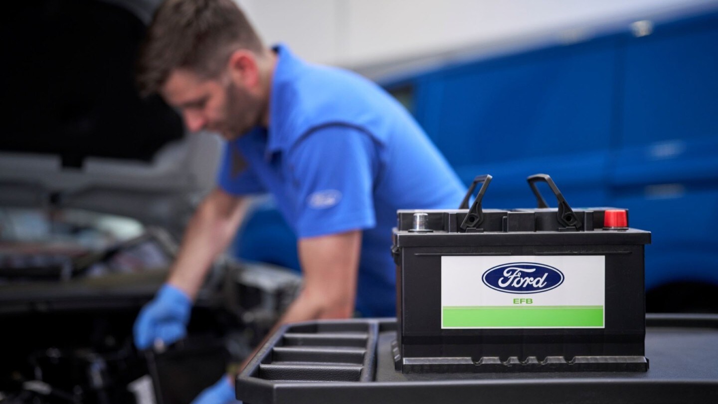 Ford Service employee fixing a vehicle with car bettery up front