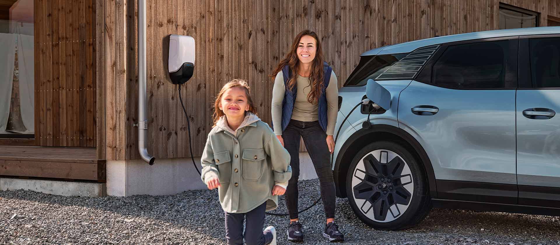 Perhe leikkii pihalla samalla, kun täyssähköinen Ford Explorer on kotilatauksessa.