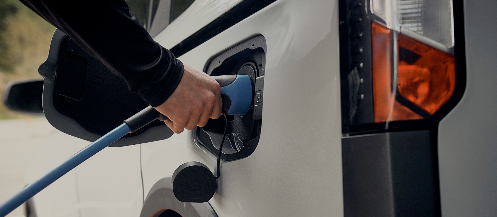 Lähikuvassa valkoinen Ford-sähköauto kytketään sähköautojen latauspisteeseen.