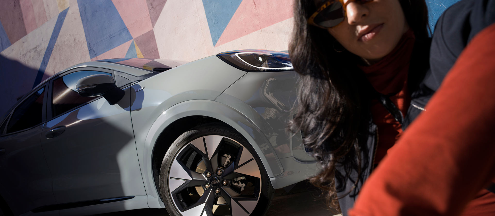 Henkilö lähellä hopeanväristä Ford Puma kevythybridi -autoa.