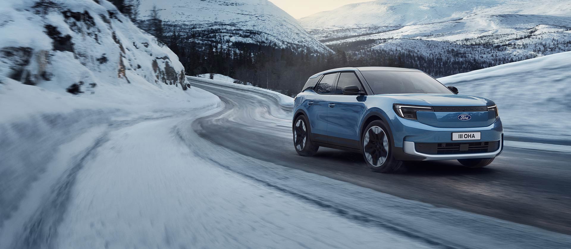 Sininen, täyssähköinen Ford Explorer ajaa lumisella vuoristotiellä tuoden esiin talvioloihin sopivat ominaisuudet ja toimintamatkan.