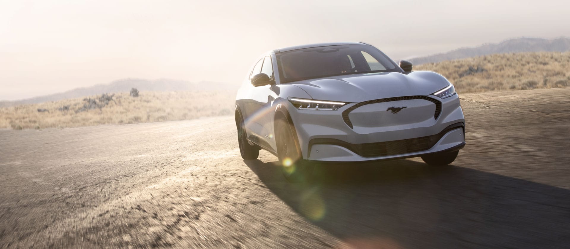 Hopeanvärinen Ford Mustang Mach-E -täyssähköauto ajaa maantiellä.