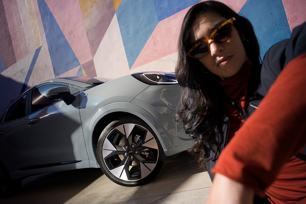 Henkilö lähellä hopeanväristä Ford Puma kevythybridi -autoa.