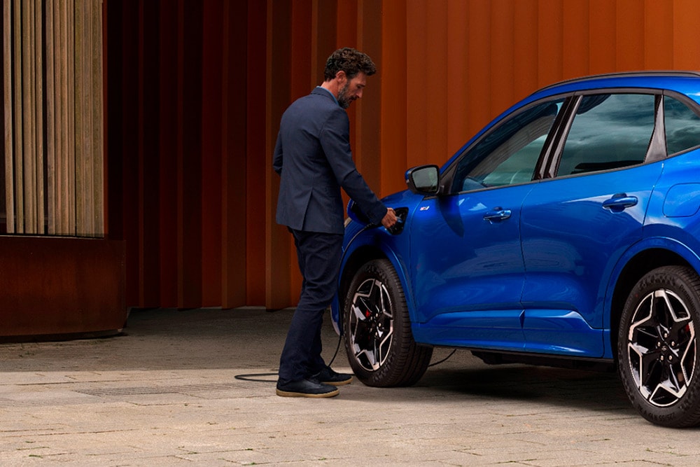 Henkilö kytkemässä sähköauton latauskaapelin Ford Kuga ladattavaan hybridiin.