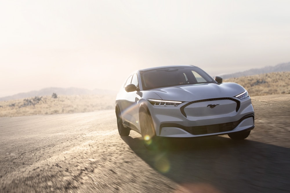 Hopeanvärinen, täyssähköinen Ford Mustang Mach-E GT ajaa maantiellä.