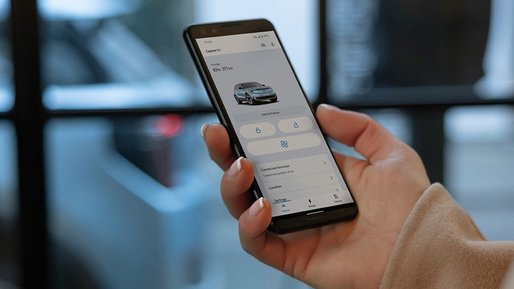 Lähikuva kädestä, jossa on älypuhelin ja sen näytöllä FordPass-sovellus.