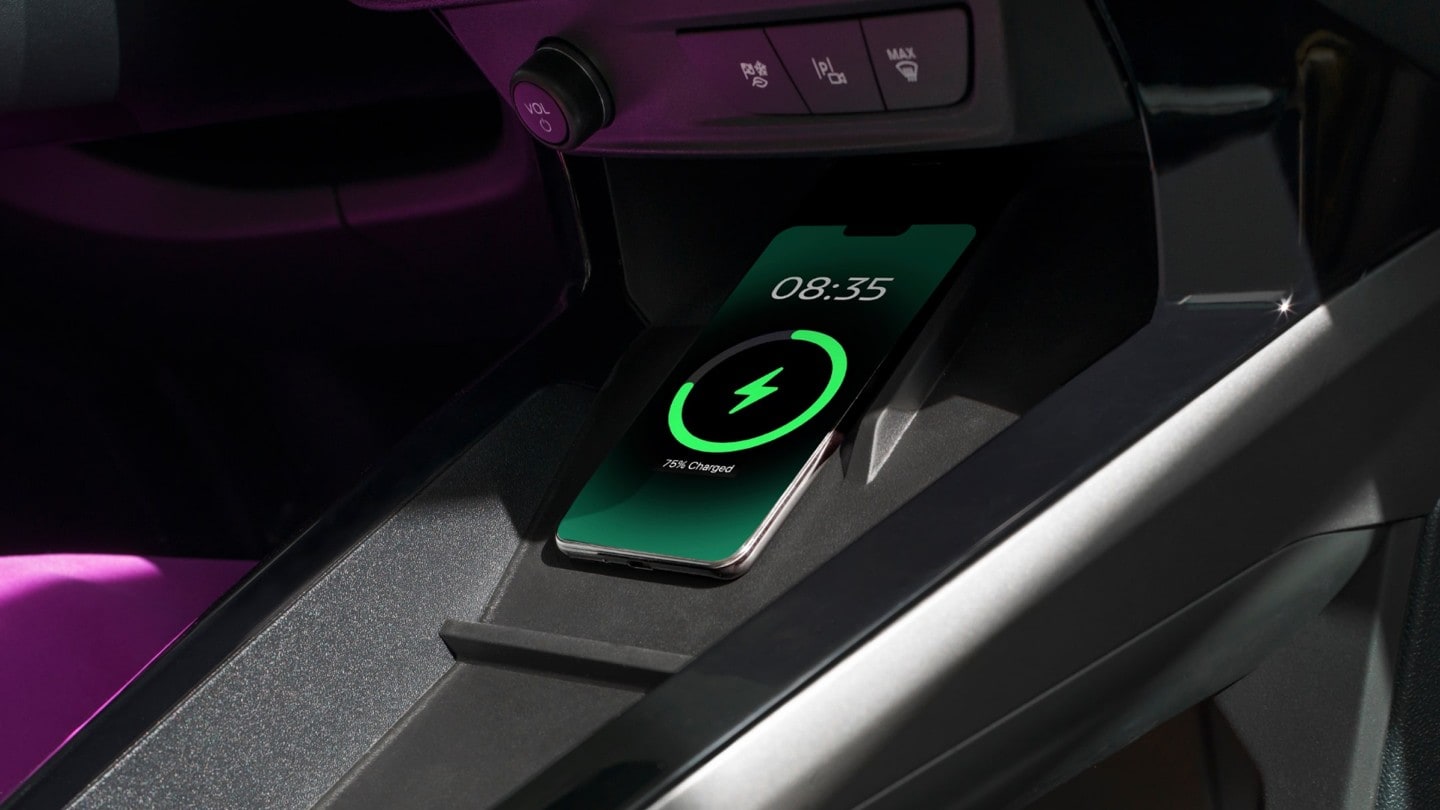 A smartphone charging on the dashboard of a Ford vehicle.