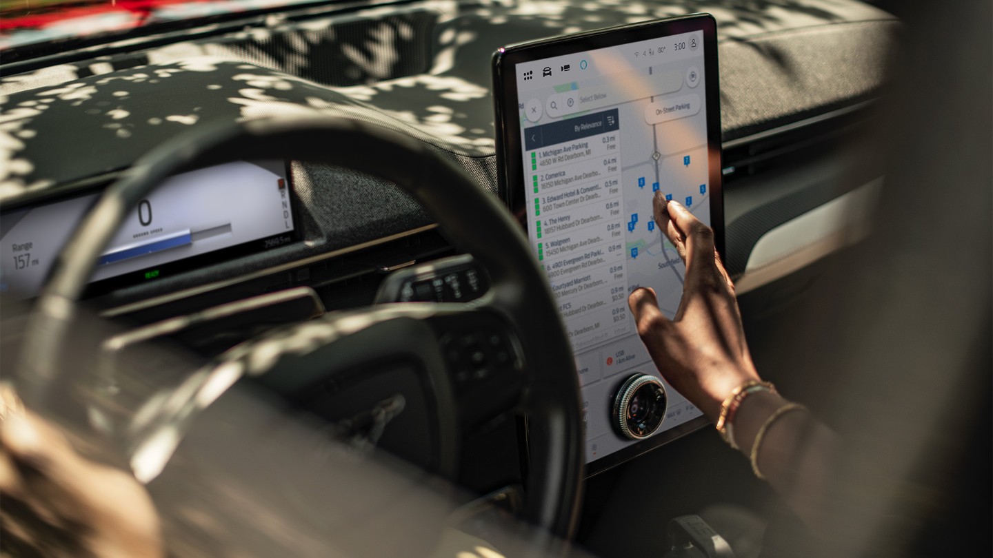 Lähikuva naisesta, joka käyttää Ford Mustang Mach-E:n suurta SYNC-kosketusnäyttöä.