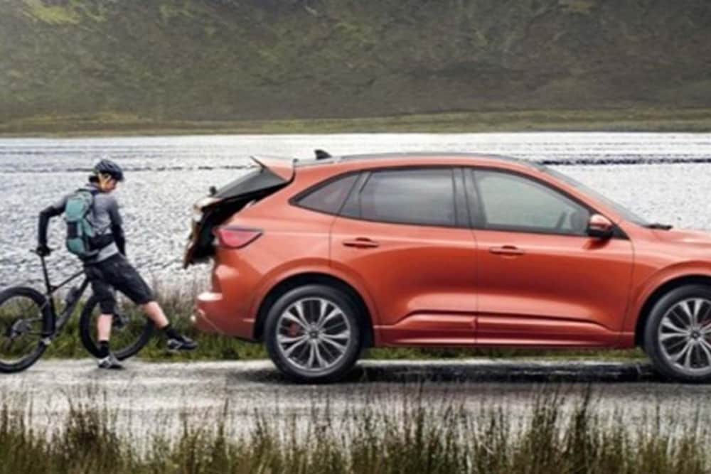 Person opening the car boot of a Ford Kuga using their foot to activate hands free tailgate technology. 