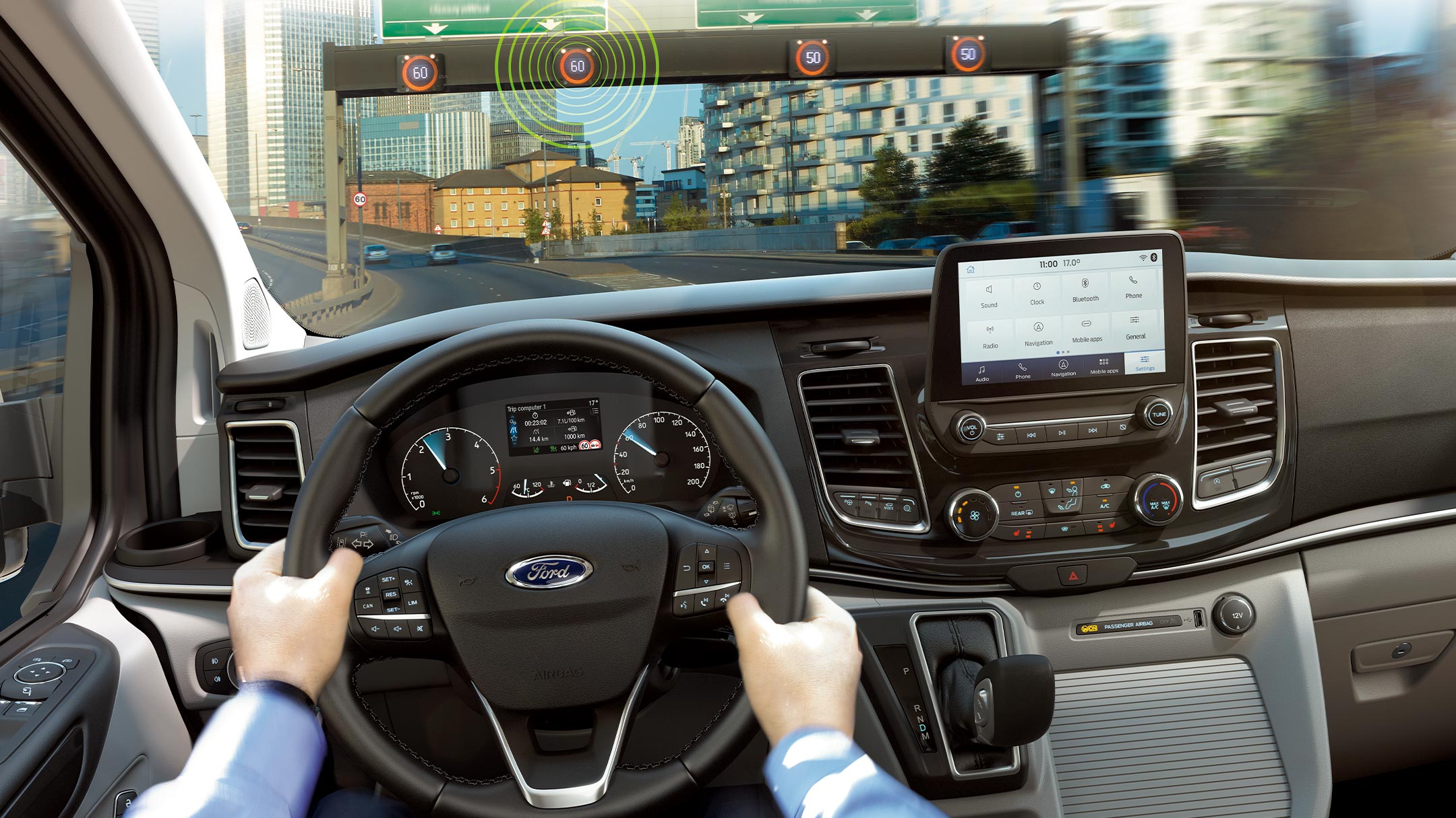 Ford interior view. Hands on the steering wheel of a Ford vehicle driving in an urban area