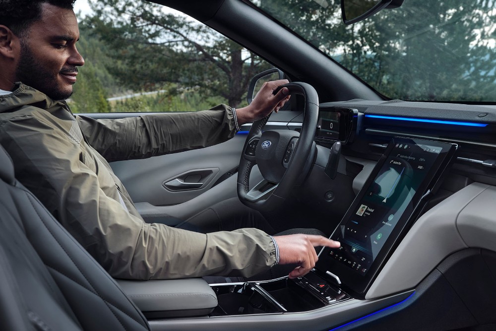 Mies istuu Ford Explorerin kuljettajan paikalla ja käyttää suurta SYNC-kosketusnäyttöä.