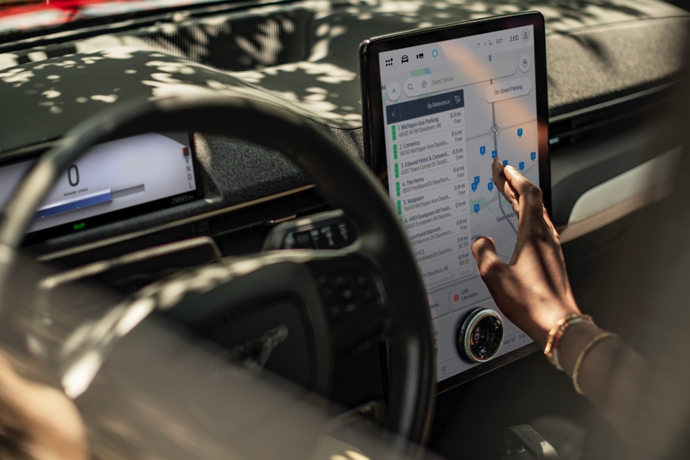 Lähikuva naisesta, joka käyttää Ford Mustang Mach-E:n suurta SYNC-kosketusnäyttöä.