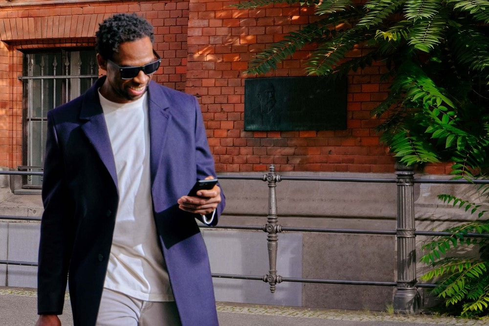 man with mobile walking near building