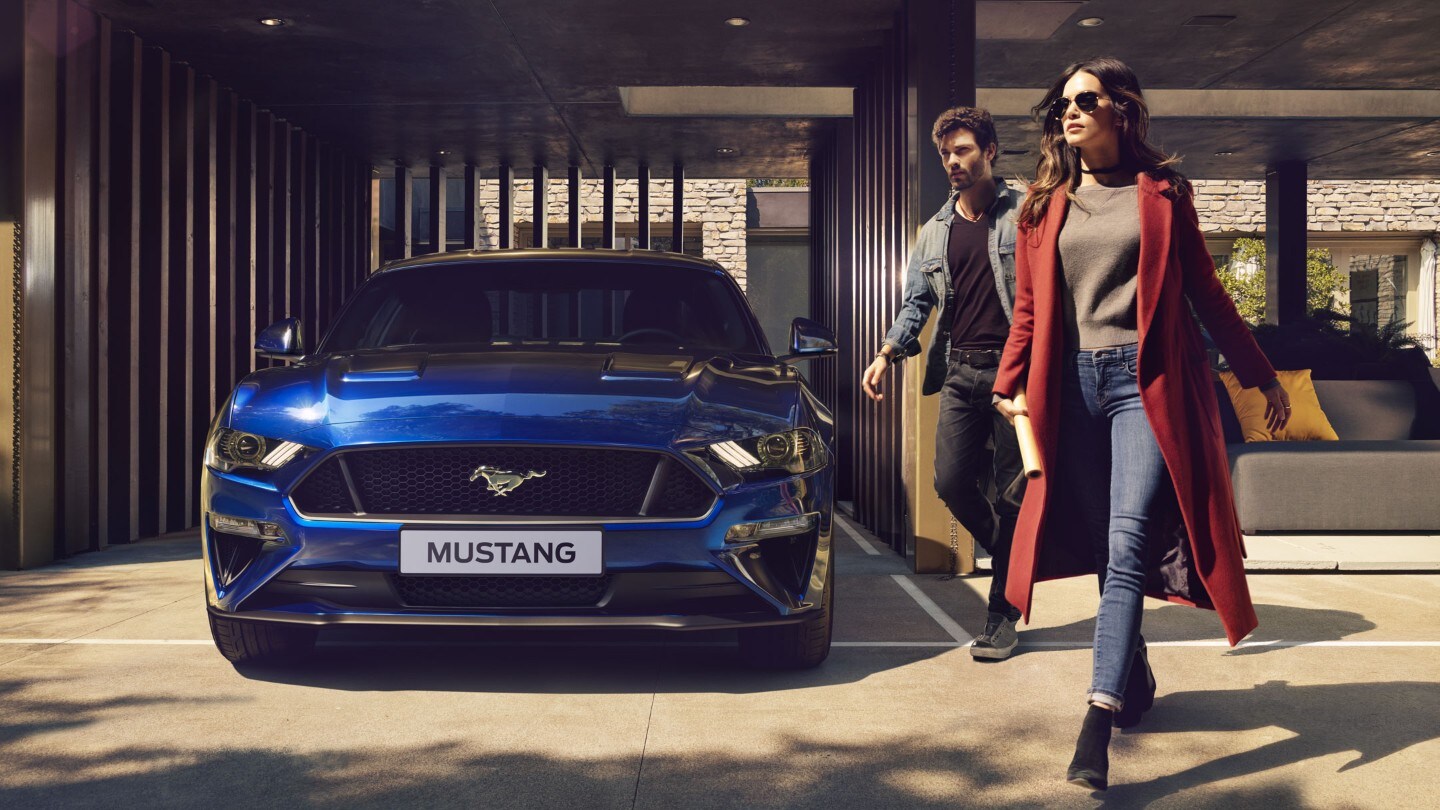 couple walking past blue Ford Mustang GT