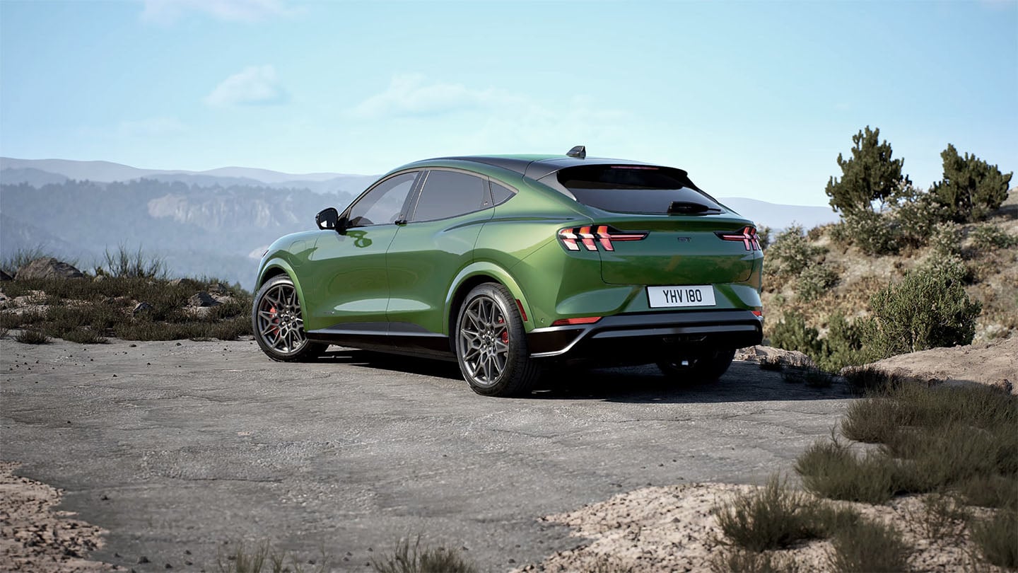 Takaa kuvattu Eruption Green -värinen Ford Mustang Mach-E GT pysäköitynä vuoristotielle.