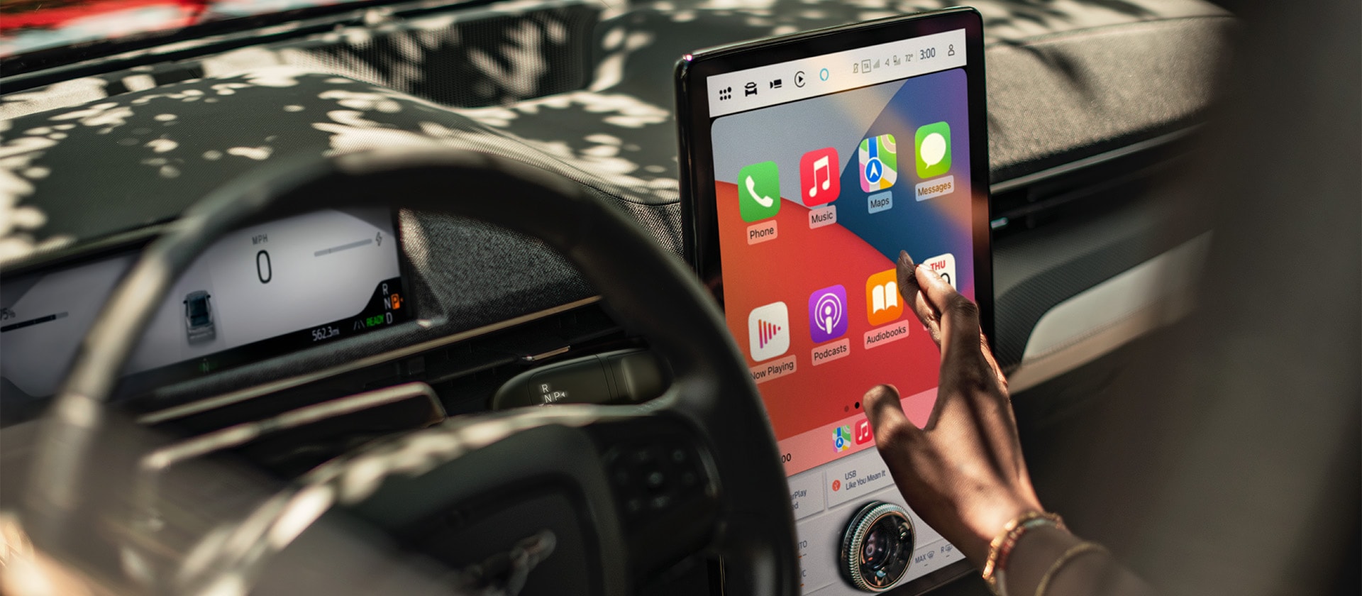 Lähikuva Ford Mustang Mach-E:n kuljettajasta käyttämässä suurta 15,5 tuuman SYNC 4 -kosketusnäyttöä, jossa on Apple CarPlay. 