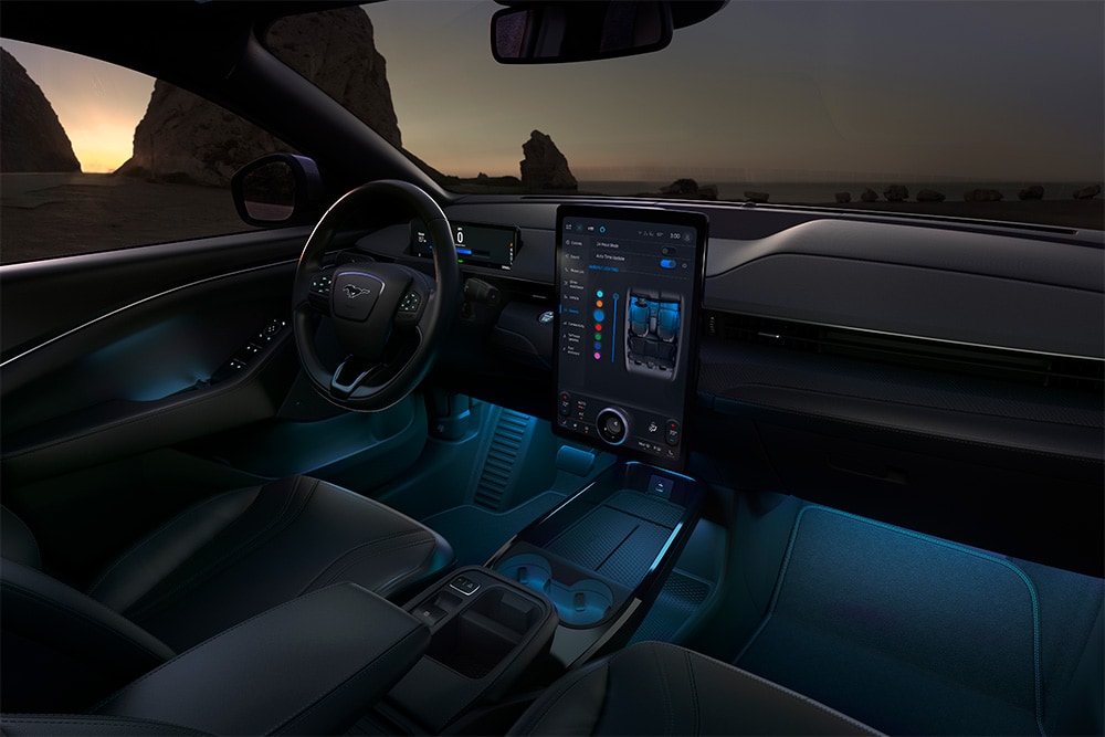 Ford Mustang Mach-E:n sisätilat illalla, kuvassa 15,5 tuuman SYNC 4 -kosketusnäyttö ja sininen LED-tunnelmavalaistus.