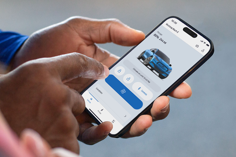 Lähikuva iPhonesta, jossa näkyy Ford-sovellus; näytöllä Ford Mustang Mach-E sekä useita sovelluspainikkeita.
