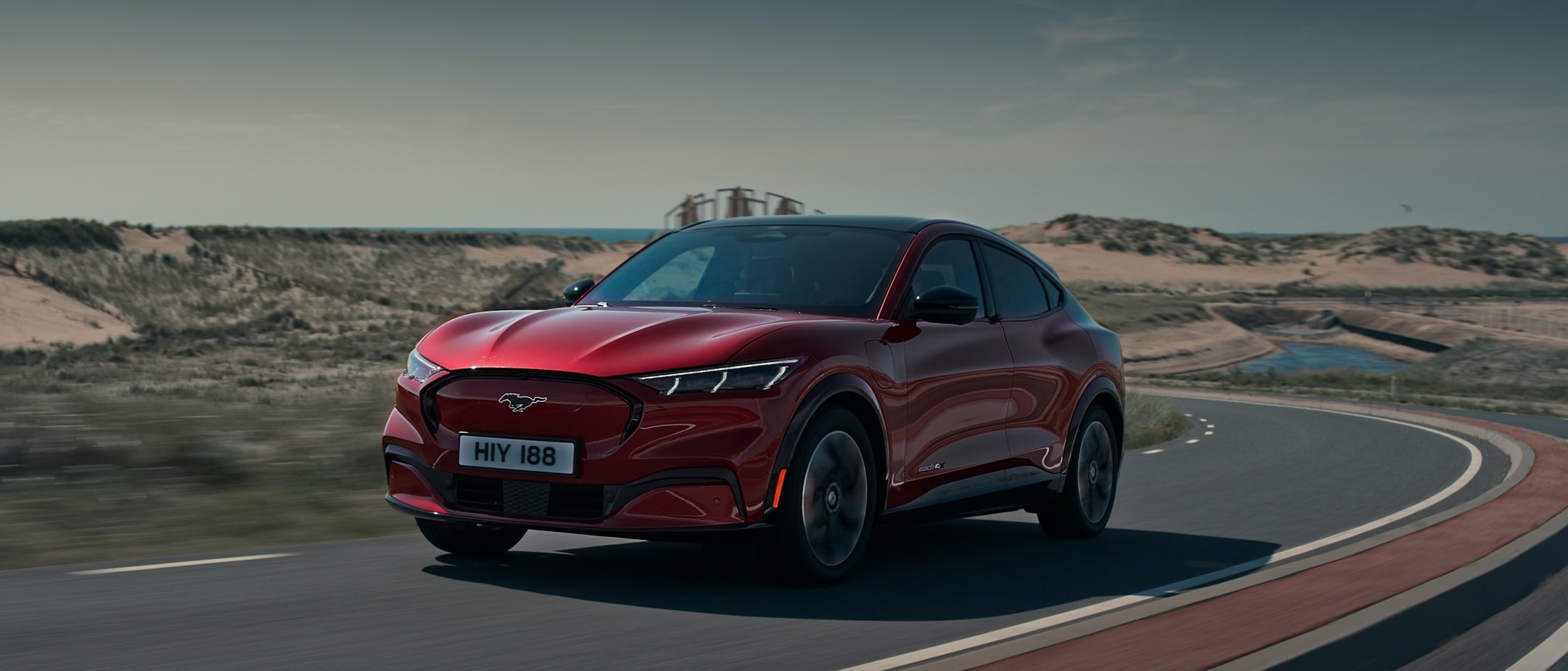 All-New red Ford Mustang Mach-E driving on beach road All-New red Ford Mustang Mach-E driving on beach road