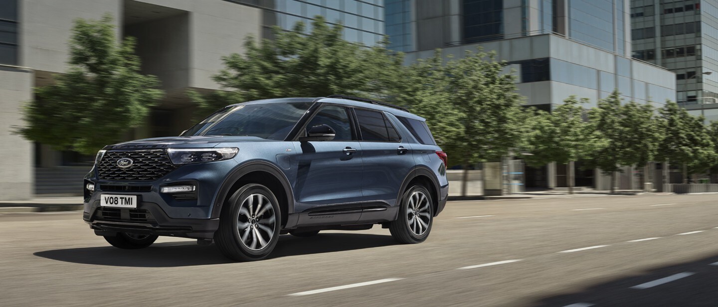 New metallic blue Ford Explorer PHEV in motion driving through city