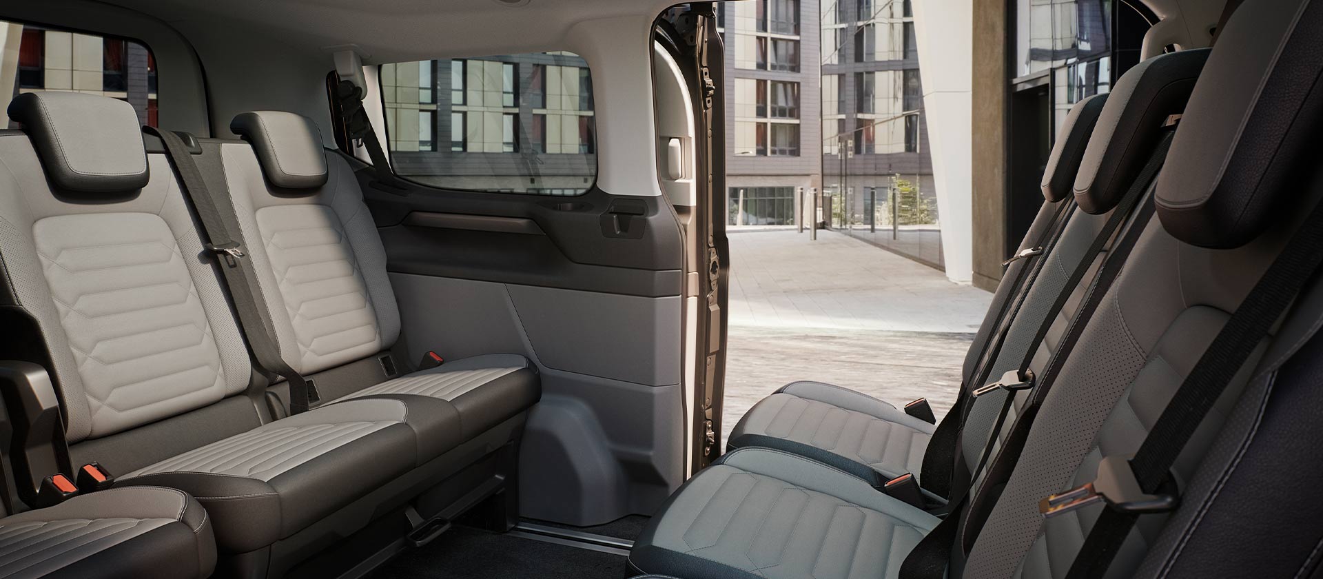 Ford Tourneo Customin sisätilat; kuvassa näkyy useita istuinrivejä harmaalla verhoilulla sekä panoraamakatto.