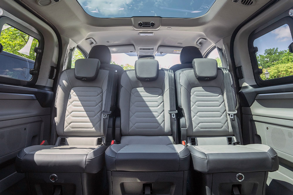 Ajoneuvon sisältä otettu kuva, jossa näkyy harmaat takaistuimet ja lasikatto.