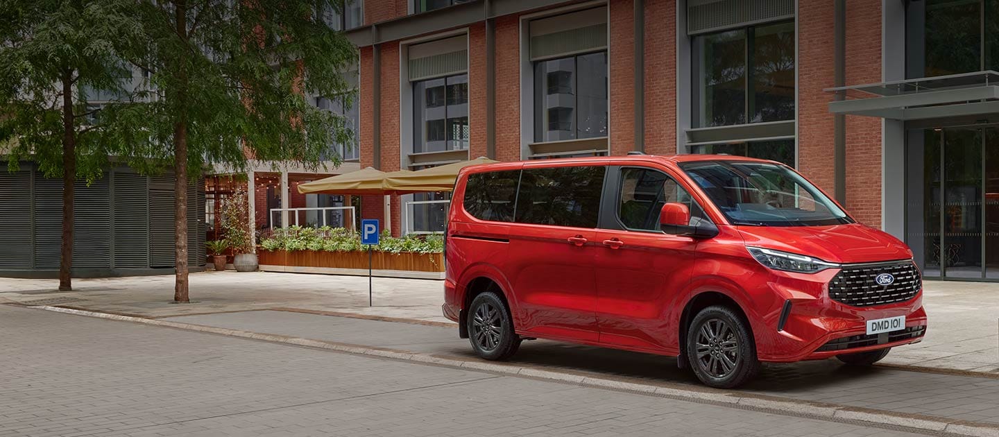 Punainen Ford Tourneo Custom pysäköitynä kaupungin kadulle. 