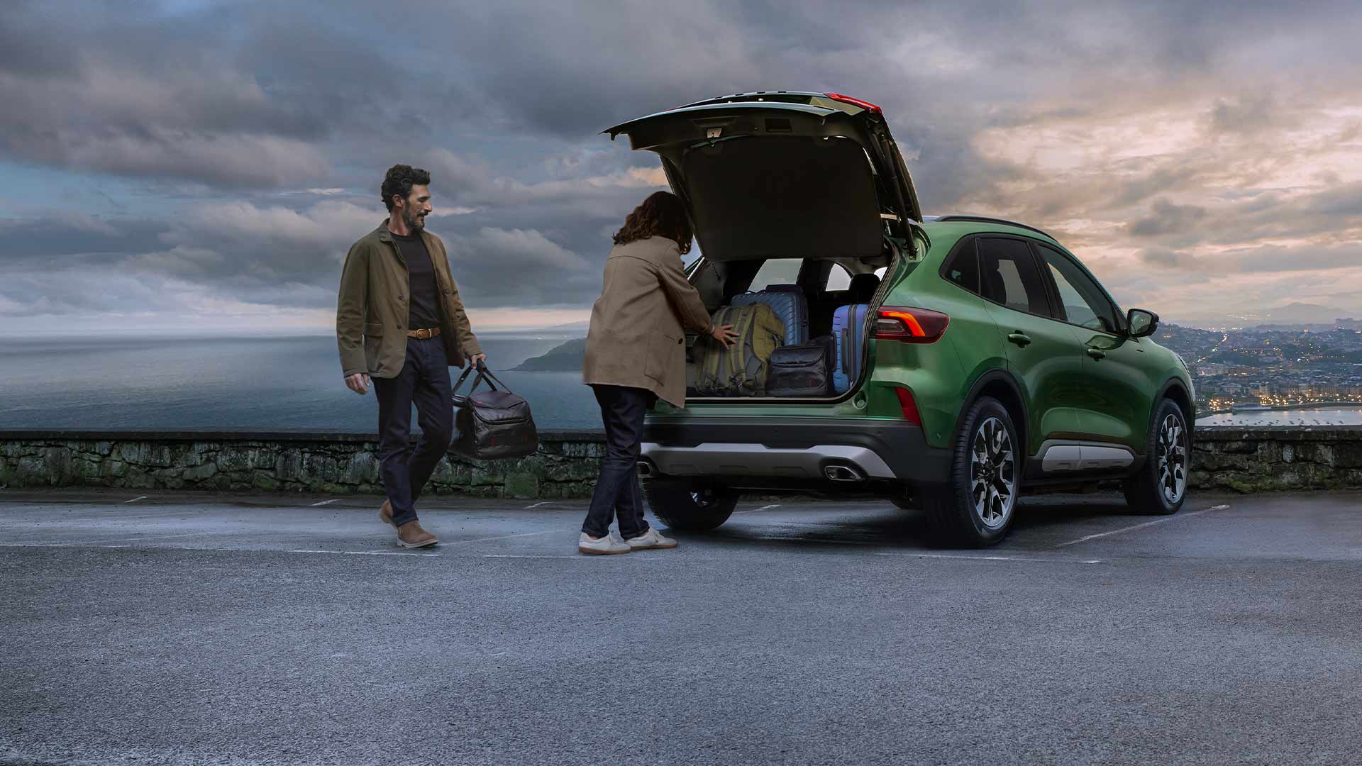 Kaksi ihmistä lastaamassa useita matkalaukkuja Ford Kugan tilavaan tavaratilaan.