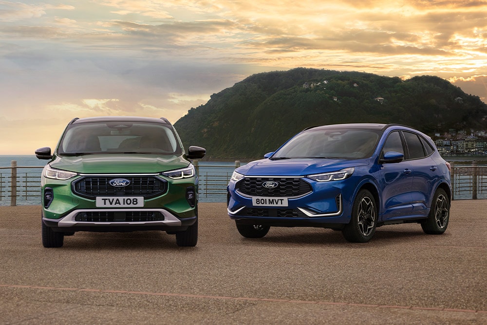 Vihreä Ford Kuga Active X ja sininen Ford Kuga ST Line X pysäköityinä rinnakkain rannikolla sijaitsevalla pysäköintialueella.