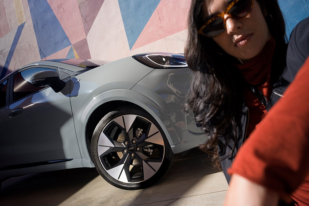 Lähikuva henkilöstä harmaan EcoBoost®-bensiinimoottorikäyttöisen Ford Puman® vieressä.