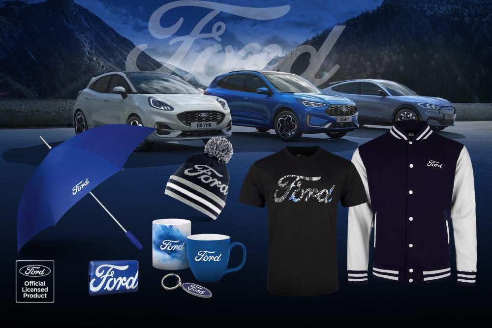Fordin tuotekokoelma, jossa taustalla näkyy erilaisia Ford-ajoneuvoja sekä Ford-brändättyjä sateenvarjoja, mukeja ja vaatteita.