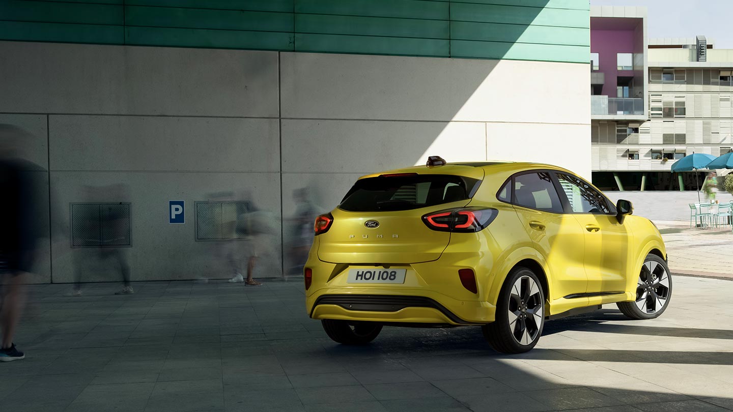Sillan alle pysäköity keltainen sähköinen Ford Puma Gen-E® kuvattuna takaa kulmasta.