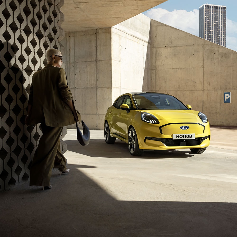 Henkilö kävelee kohti uutta keltaista sähköistä Ford Puma Gen-E:tä®.