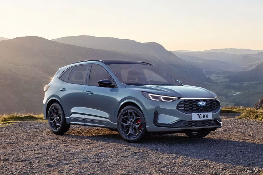 Harmaa Ford Kuga pysäköitynä soratielle vuoristoon auringonlaskun aikaan.