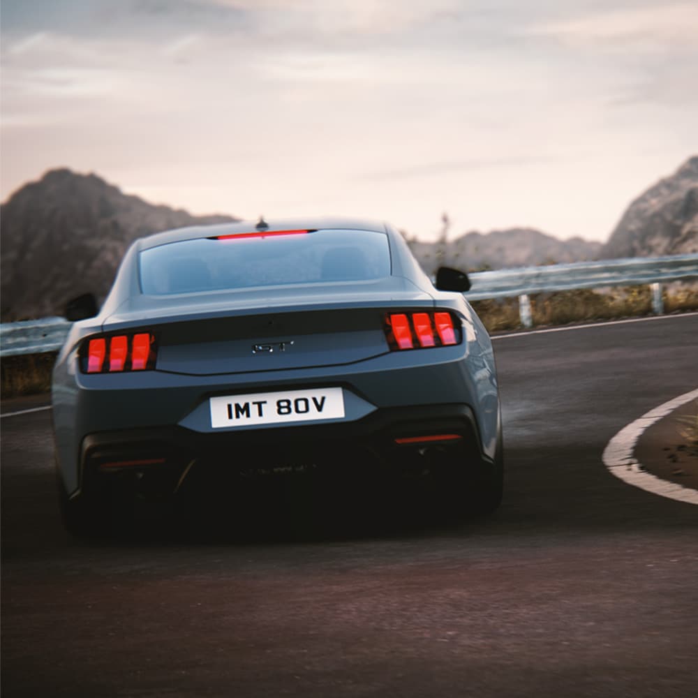 Ford Mustang GT Fastback Vapor Blue ulkovärillä. Auto kuvattu takaa jyrkässä mutkassa.