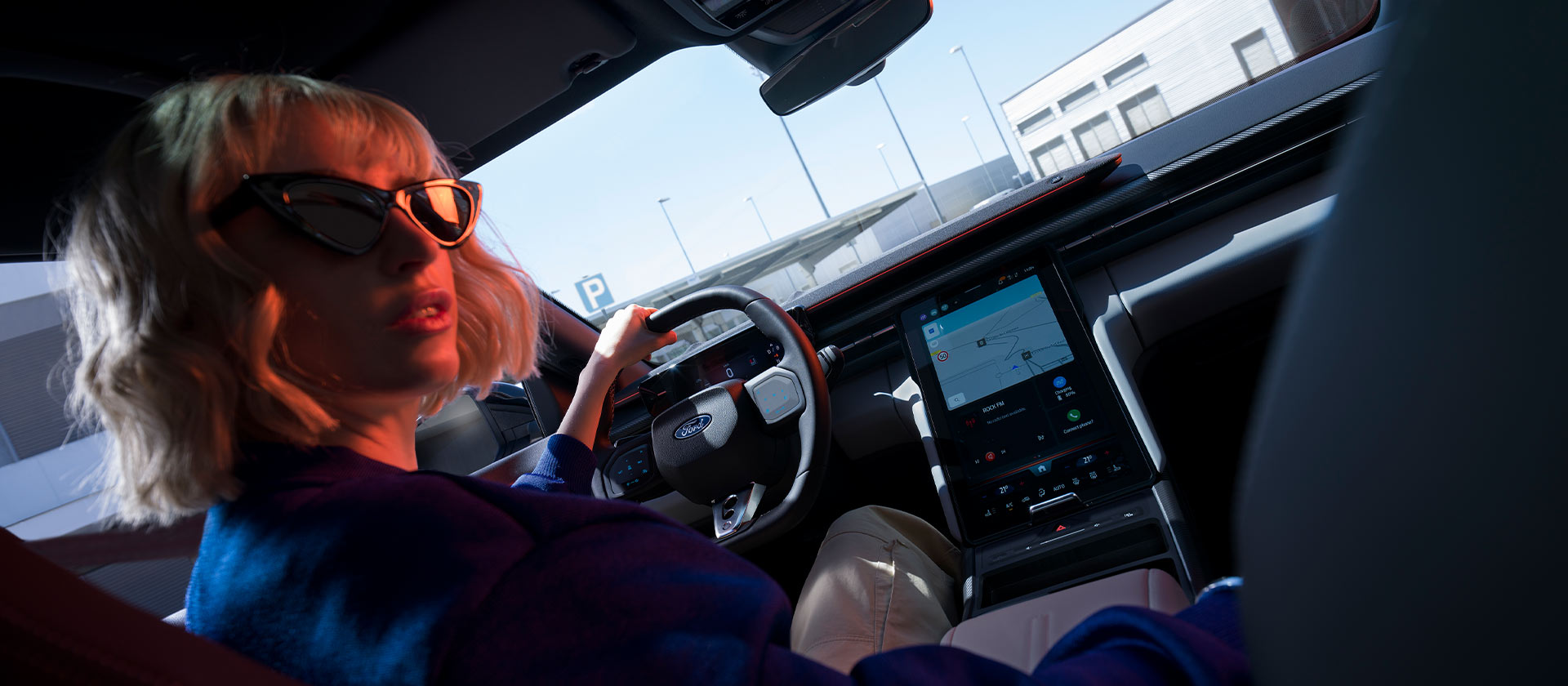 Nainen istuu Ford Caprin kuljettajan paikalla. Kuvassa näkyy ohjauspyörä ja suuri SYNC® Move -kosketusnäyttö.