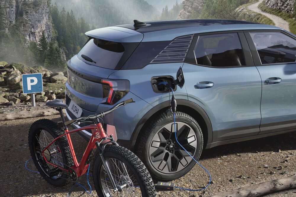 Sähköpyörä latautuu Ford Explorerin® avulla. Vuorimaisema taustalla.