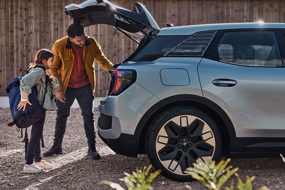 Isä ja tytär laittamassa tavaraa hopeanvärisen Ford Explorerin® tavaratilaan.