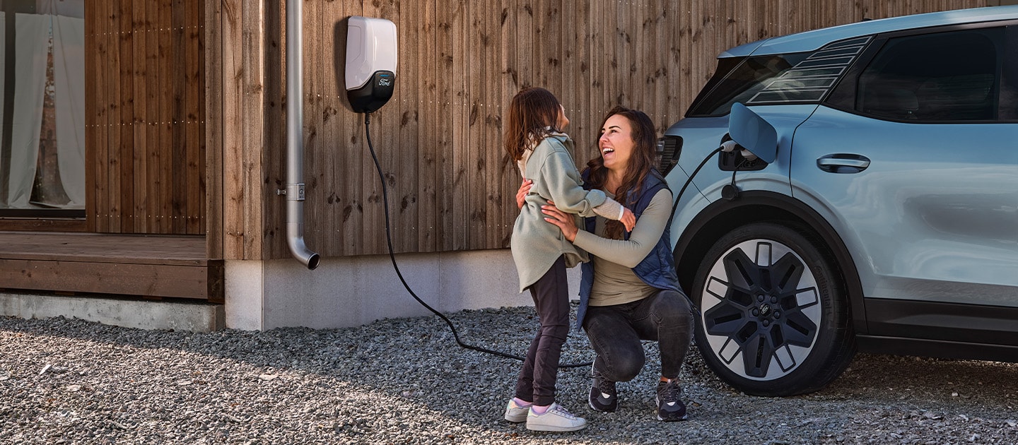 Person and child next to a charging Ford Explorer