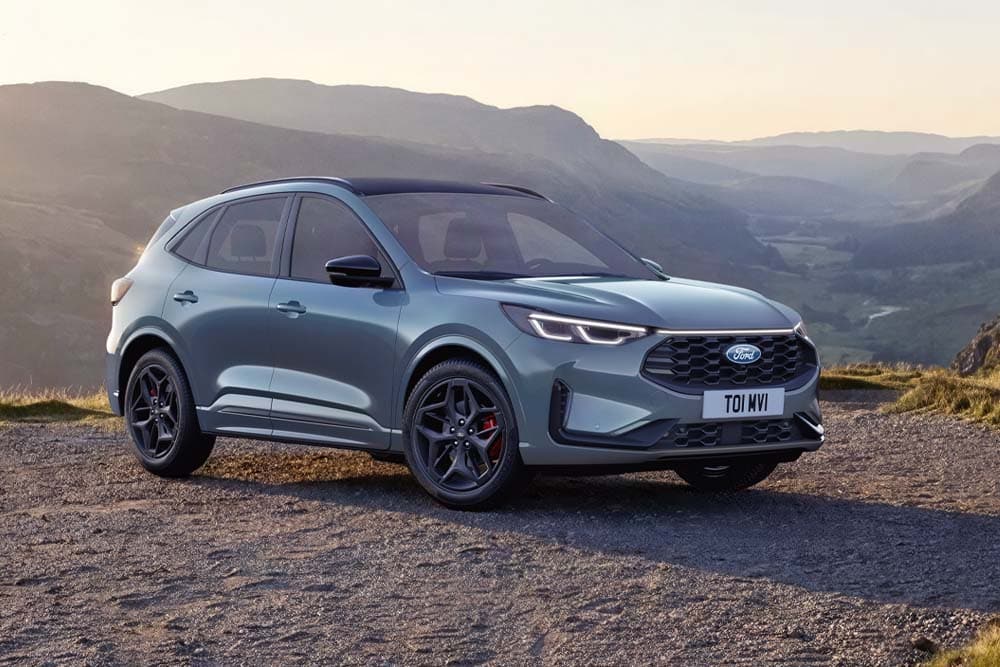 Harmaa Ford Kuga pysäköitynä soratielle vuoristoon auringonlaskun aikaan.