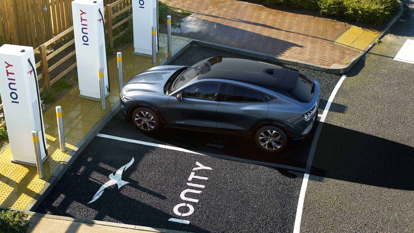 A woman charging an all-new Ford Mustang Mach-E at an IONITY charging station