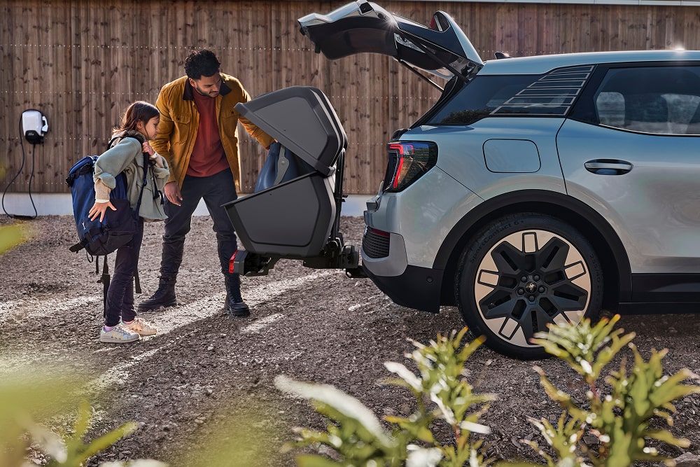 Mies ja lapsi Ford Explorer -katumaasturin avoimen tavaratilan vierellä laittamassa taitettuja lastenrattaita autoon sisään.