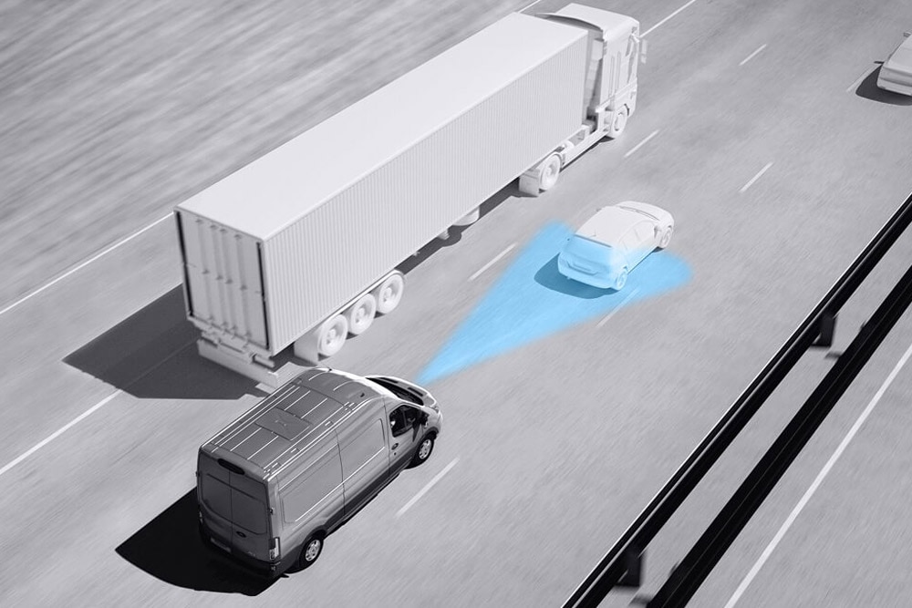Harmaasävypiirros Ford Transit Vanista; siniset viivat tiellä kuvaavat kuljettajaa avustavien edistyksellisten järjestelmien käyttöä.