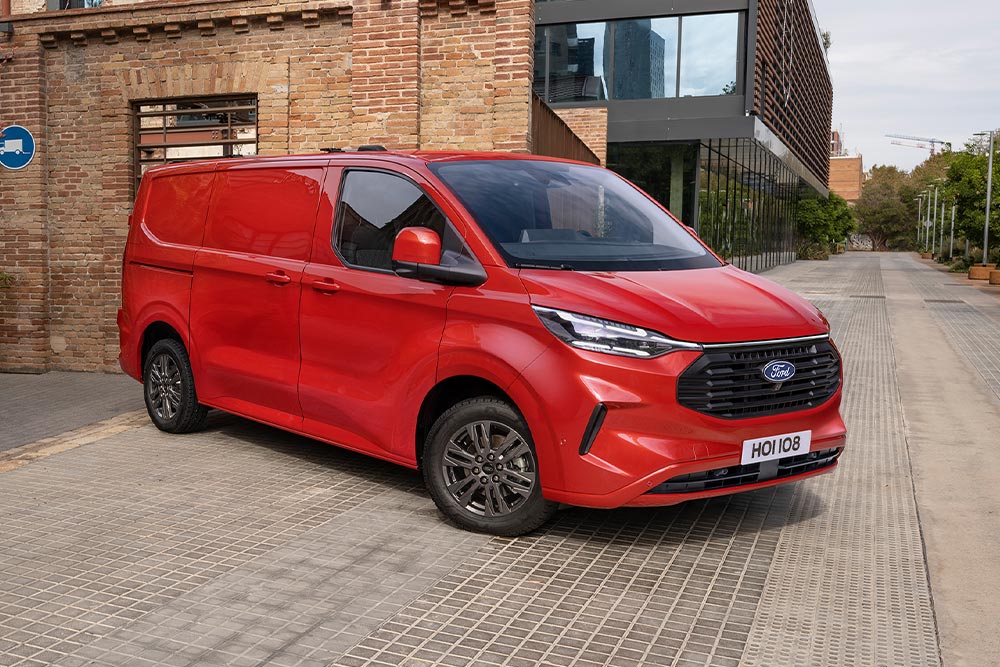 Punainen Ford Transit Custom -pakettiauto pysäköitynä kadun varteen.