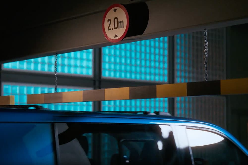 Sininen sähköinen Ford E-Transit Custom -pakettiauto ajamassa parkkihalliin.