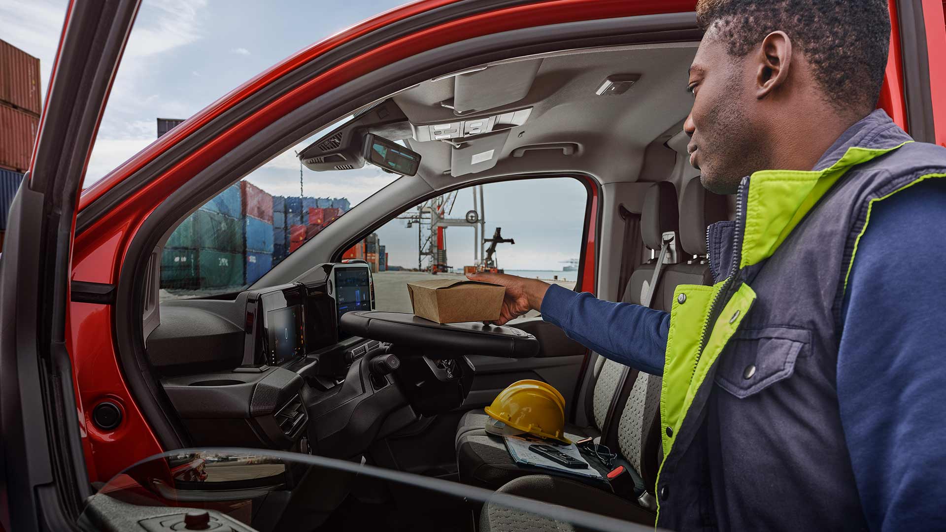 Henkilö laittamassa pakettia punaiseen Ford Transit Customiin.