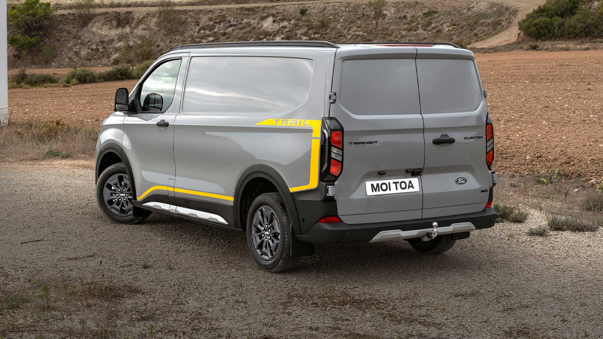 Harmaa Ford Transit Custom Trail -pakettiauto takaa kuvattuna.