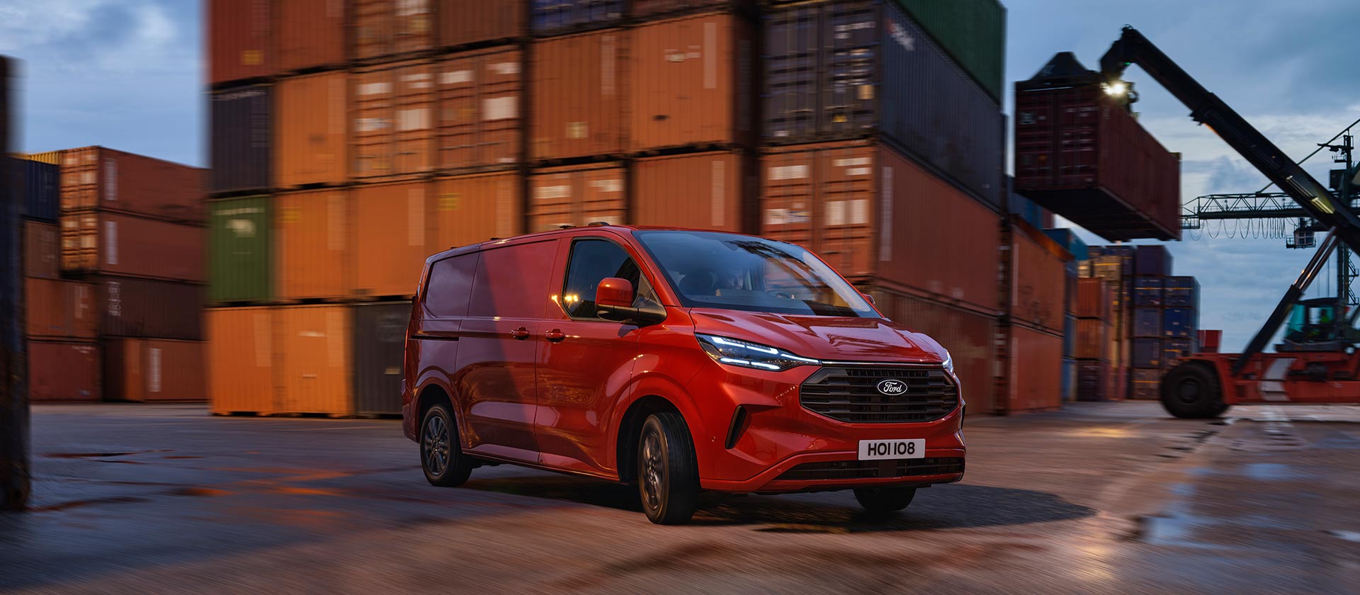 Punainen Ford Transit Custom -pakettiauto ajamassa sataman pihalla.
