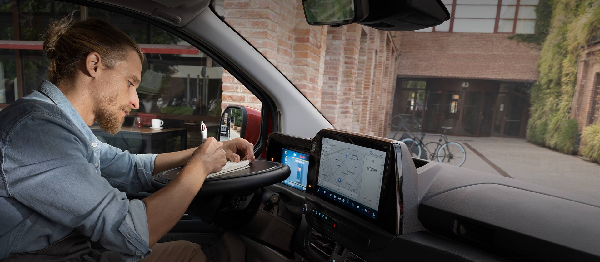 Henkilö kirjoittamassa muistioon Ford Transit Customissa.