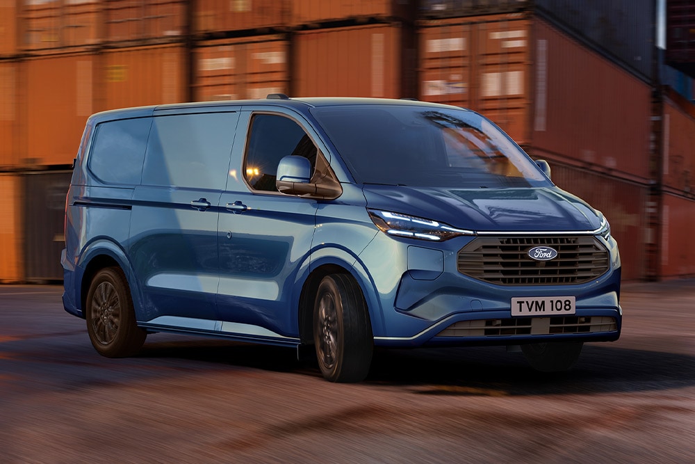 Sininen Ford Transit Custom ladattava hybridi -pakettiauto ajamassa sataman pihalla.